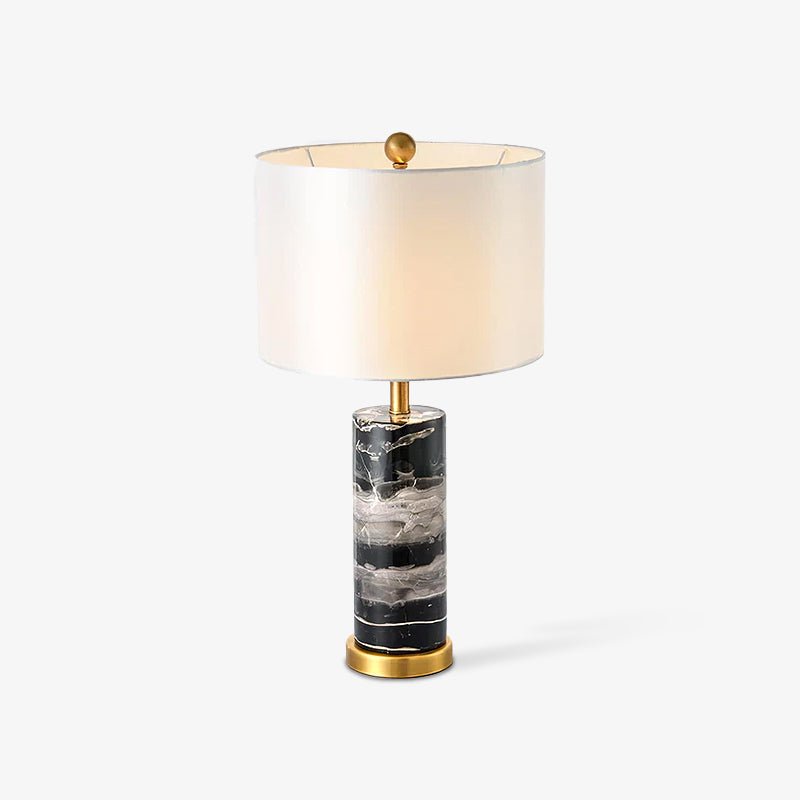 A Clérachic table lamp stands on white, its cream drum shade paired with a veined black marble base.