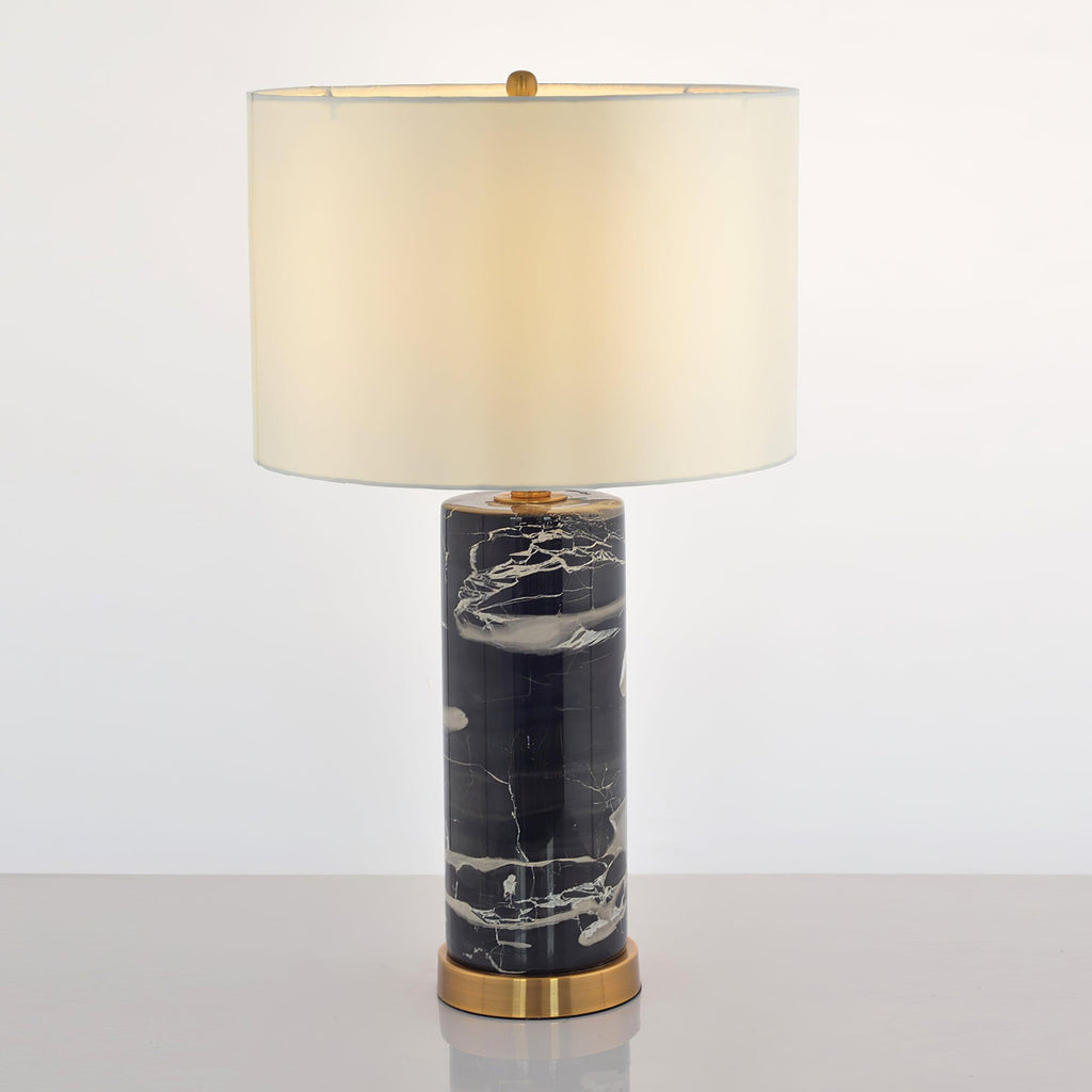 Full-length view of the Clérachic table lamp, its ivory shade glowing warm above the marbled black column base.
