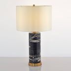 Full-length view of the Clérachic table lamp, its ivory shade glowing warm above the marbled black column base.