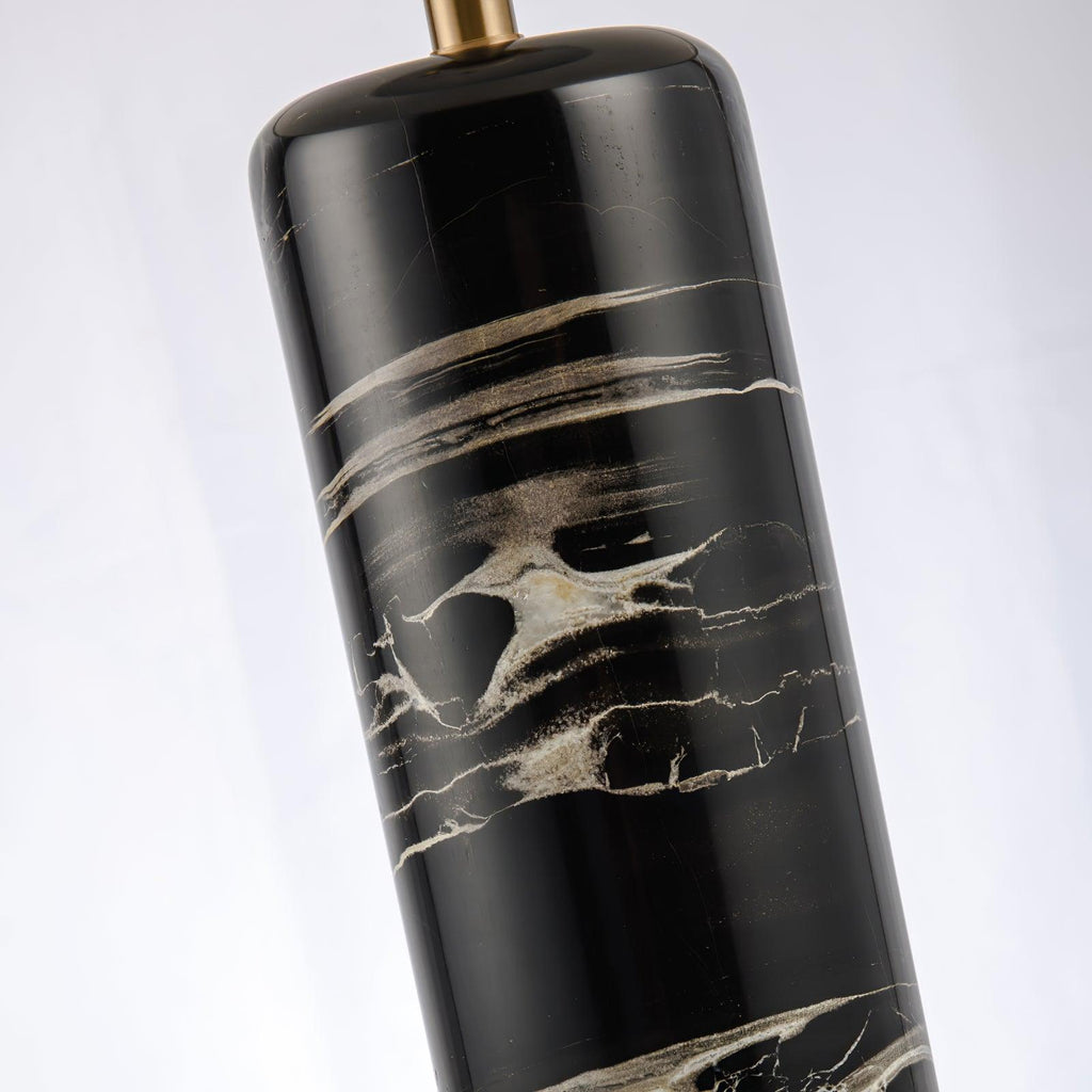 A diagonal close-up of the Clérachic table lamp's marble column and brass cap, cropped tight on the texture.