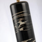 A diagonal close-up of the Clérachic table lamp's marble column and brass cap, cropped tight on the texture.