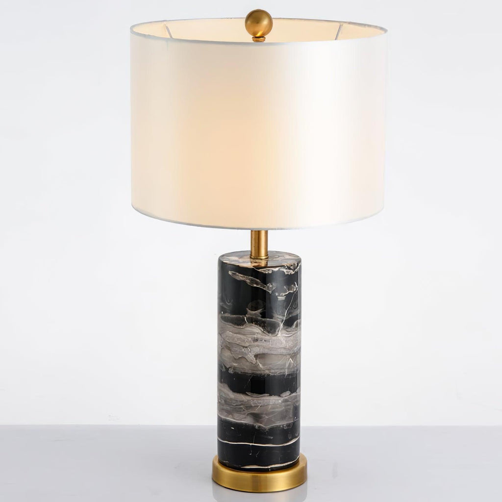 Close full-length shot of the Clérachic table lamp on white, its lit shade set above the black marble base.