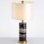 Close full-length shot of the Clérachic table lamp on white, its lit shade set above the black marble base.