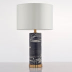 The Clérachic table lamp stands on grey, its pale drum shade paired with a black marble base veined in grey.