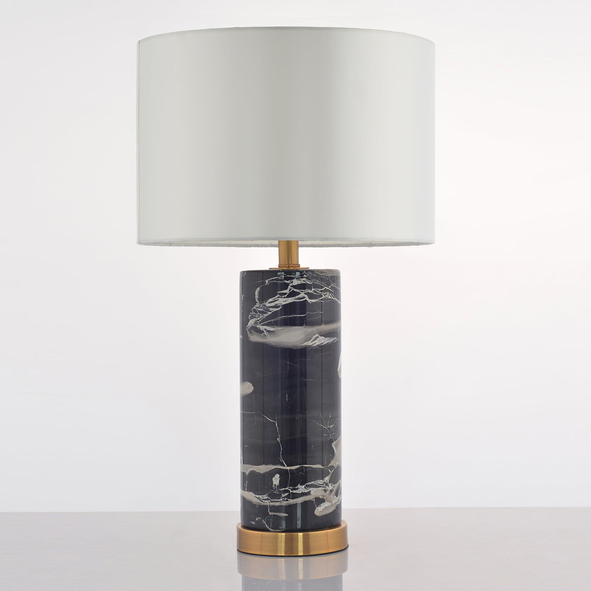 The Clérachic table lamp stands on grey, its pale drum shade paired with a black marble base veined in grey.