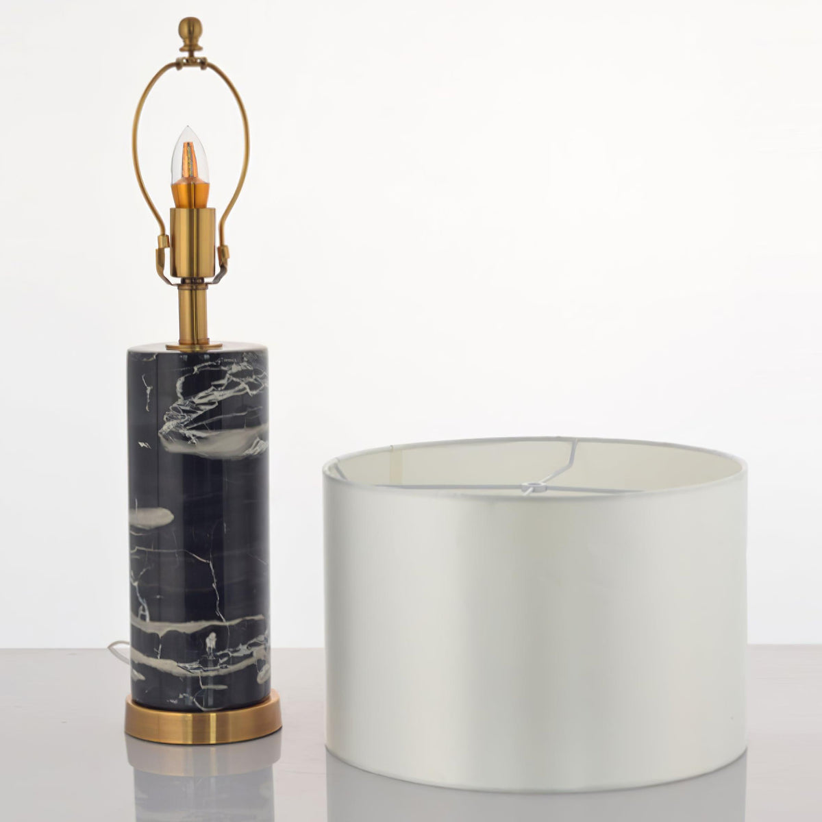 This Clérachic table lamp is shown apart from its shade, the bare bulb and brass socket set beside the drum shade.