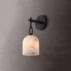 This matte-black Clérachic sconce holds its dome alabaster shade unlit against a plain grey wall.