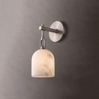 A brushed-nickel Clérachic wall sconce casts warm light through its alabaster dome shade on a charcoal-grey wall.