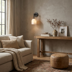 A black-hardware Clérachic wall light glows above a console table set with dried branches and a stoneware vase.