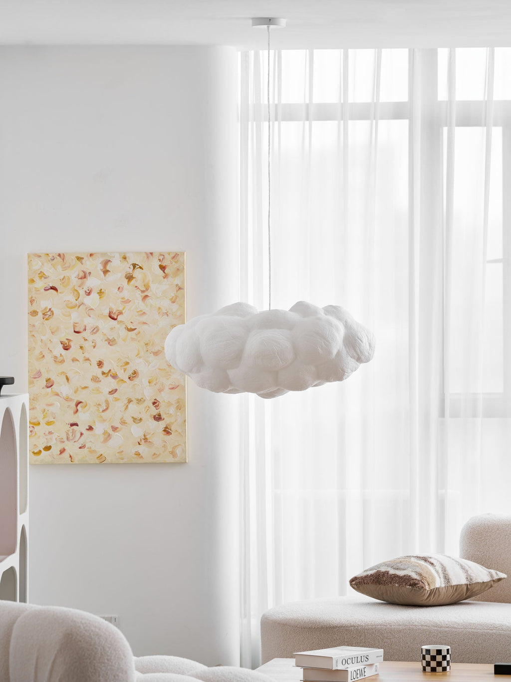 Unlit, this Clérachic cloud-shaped pendant hangs in a bright room with sheer curtains and a cushioned bench.