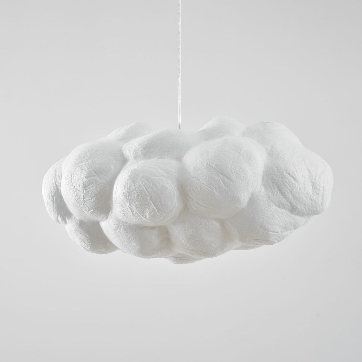 Unlit and shown from the side, this Clérachic cloud-shaped pendant sits against plain grey.