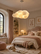 This Clérachic cloud pendant lights a bedroom with a canopy bed and a pink knitted pouf.