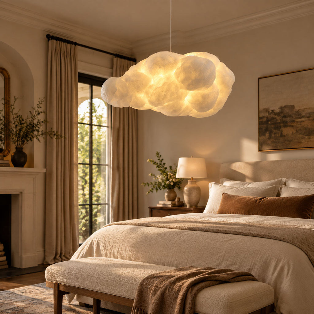 This Clérachic cloud pendant glows warm above a bed in a room with a lit fireplace.