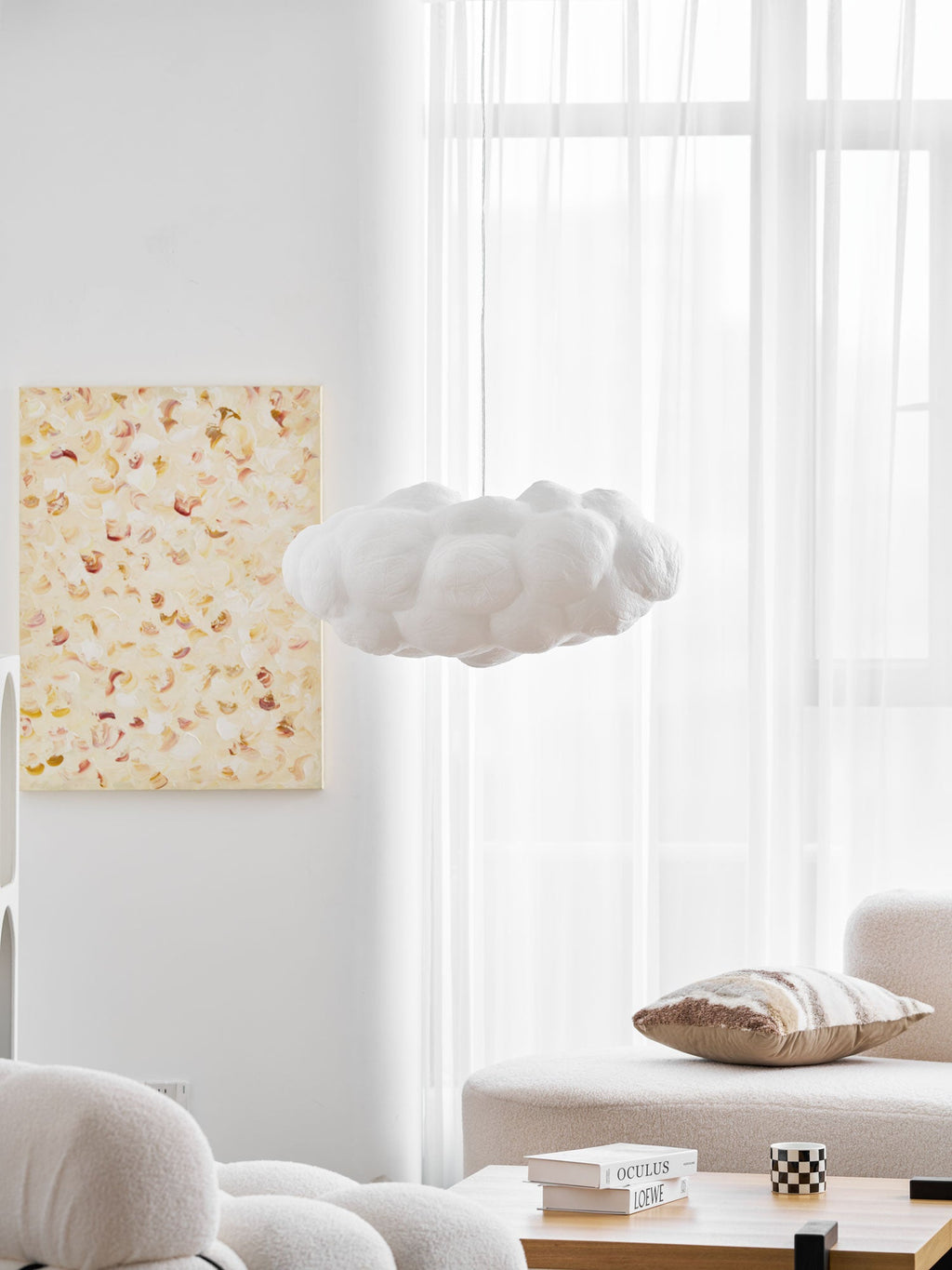 Unlit, this Clérachic cloud-shaped pendant hangs beside a framed floral print near a sheer curtain.