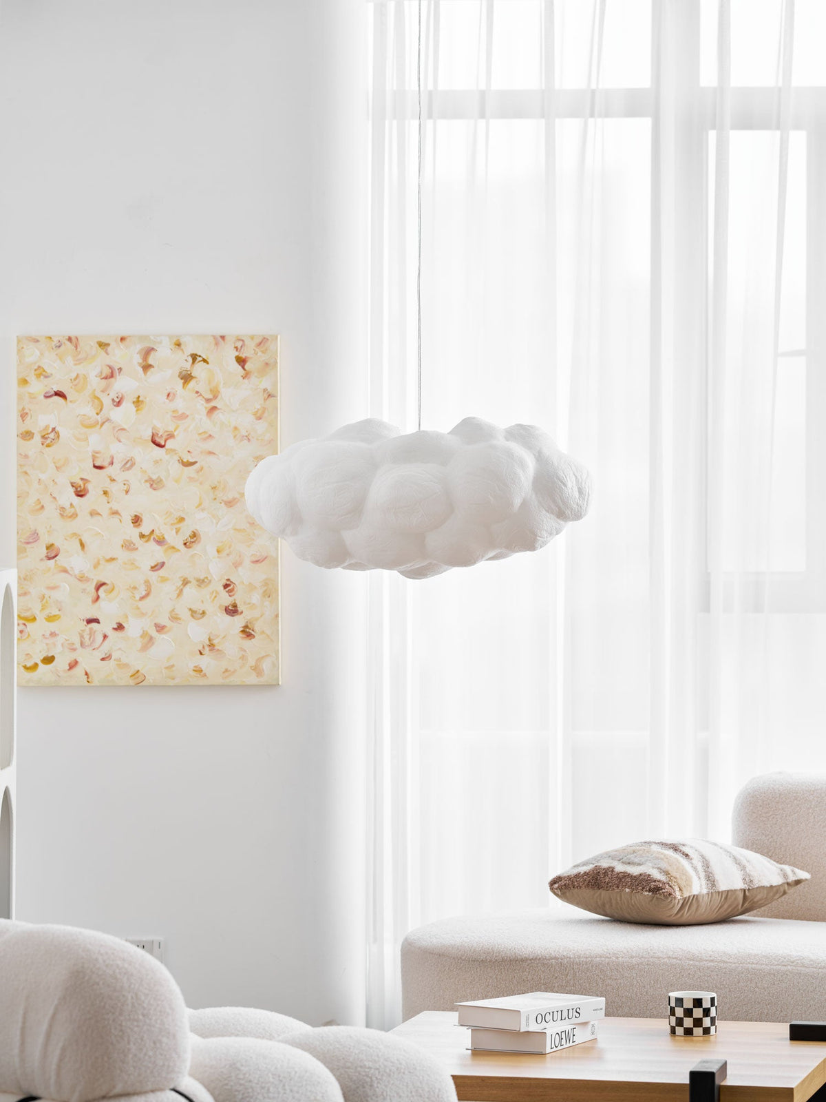 Unlit, this Clérachic cloud-shaped pendant hangs beside a framed floral print near a sheer curtain.
