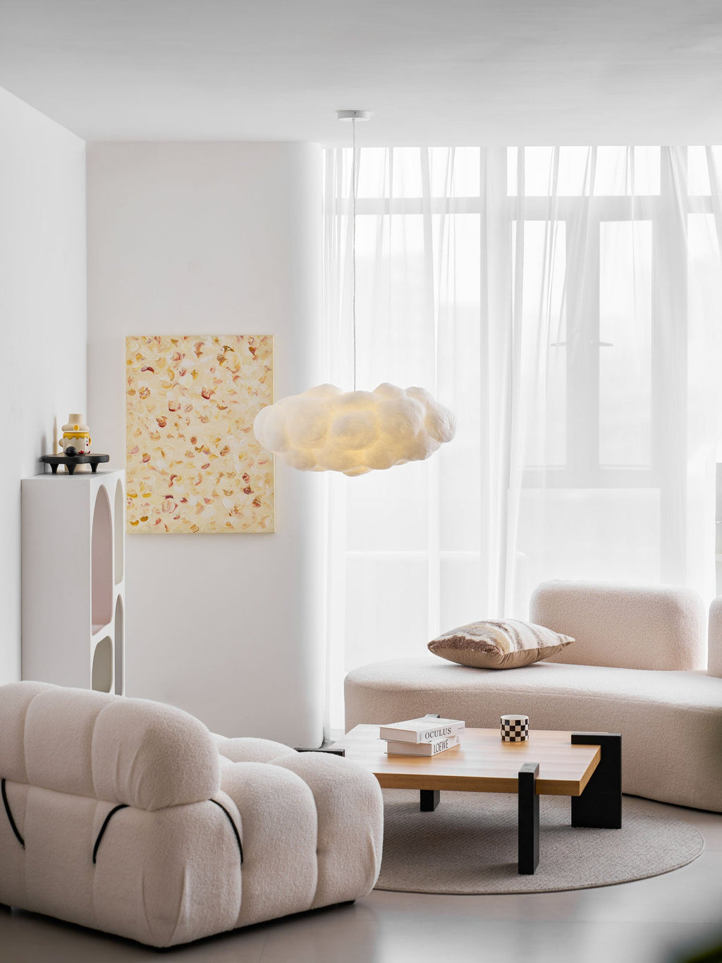 This Clérachic cloud-shaped pendant glows warm above a cream sofa in a sheer-curtained living room.
