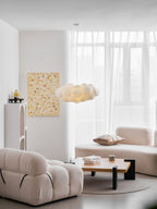 This Clérachic cloud-shaped pendant glows warm above a cream sofa in a sheer-curtained living room.