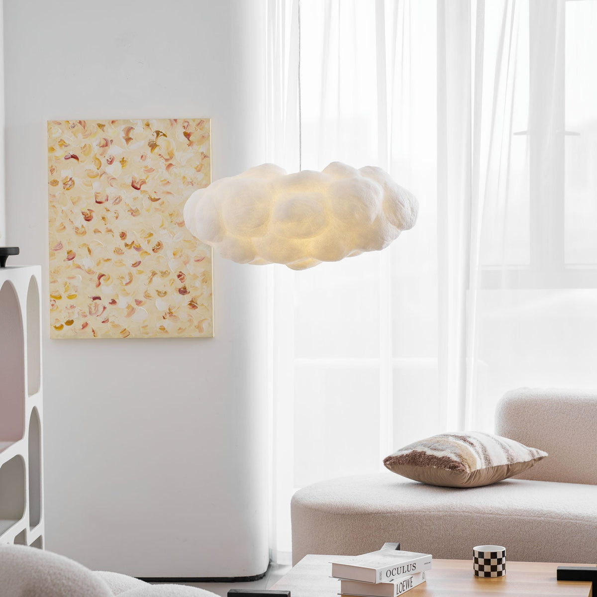 This Clérachic cloud-shaped pendant glows beside a framed print, a cushioned sofa and sheer curtains.