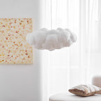 Set against a plain wall, this unlit Clérachic cloud-shaped pendant hangs beside a framed floral print.