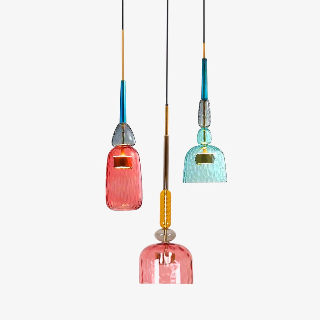A coral bottle shade and a teal bell shade hang behind a second, closer coral shade on this Clérachic pendant, on white.