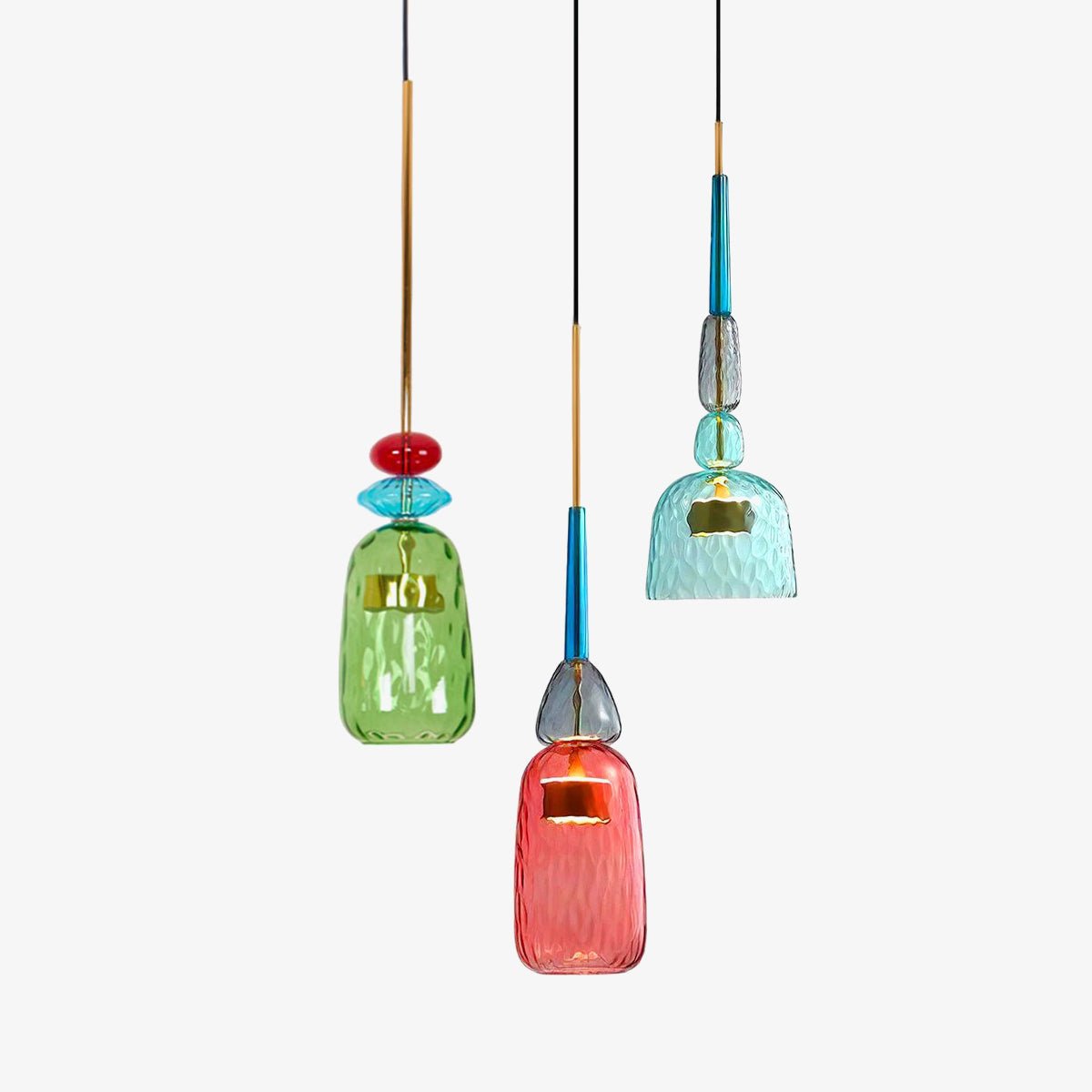 Three Clérachic pendants, green, coral and teal glass shades, hang at staggered heights on a plain white background.