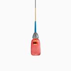 A single smooth coral glass cylinder shade hangs from a blue stem on this Clérachic pendant, shown on white.