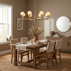Above a dining table set beneath a round mirror and wood sideboard, this Clérachic chandelier's brass arms cross in a starburst pattern.