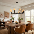 Beneath a coffered ceiling, this Clérachic chandelier's black finish hangs above a table with tan leather chairs.