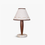 Clérachic linen cone-shade lamp with a tapered walnut stem and round marble base, shown alone against a pale studio backdrop.