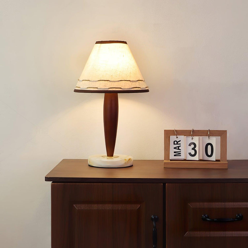 Clérachic lamp lit on a dark wood dresser next to a small wooden flip calendar reading 30 March.