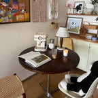 Clérachic lamp lit on a round table beside a coffee maker, framed art and a wicker basket hanging on the wall.