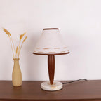 Clérachic table lamp standing unlit on a sideboard beside a wheat-stem vase, its cord trailing across the wood.