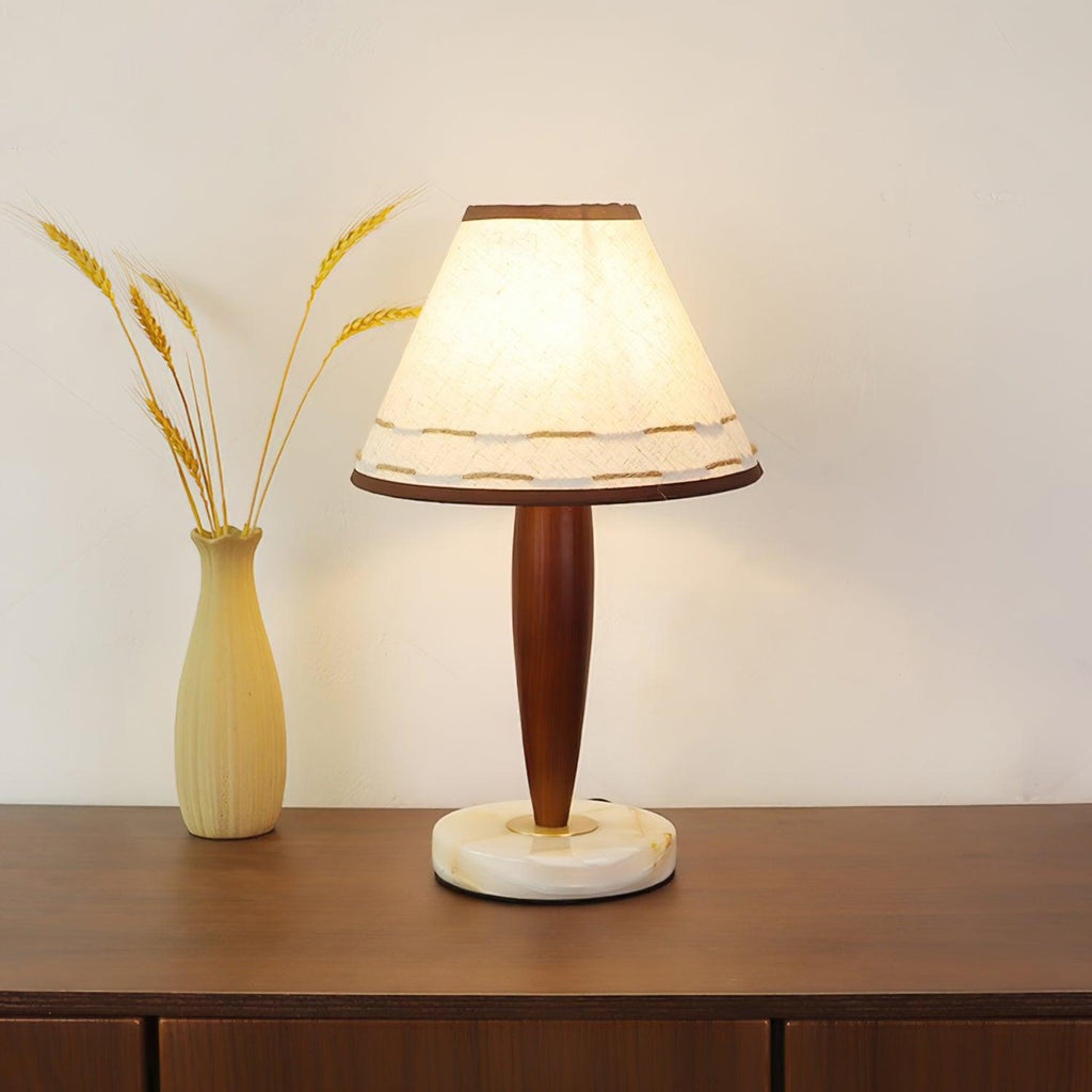 Lit Clérachic lamp beside a dried-wheat vase on a walnut sideboard, cropped closer to show the glowing shade in full.