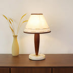Lit Clérachic lamp beside a dried-wheat vase on a walnut sideboard, cropped closer to show the glowing shade in full.