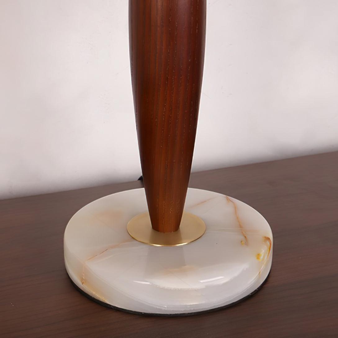 Close-up of the Clérachic lamp's tapered walnut stem meeting its round marble base at a brass collar.