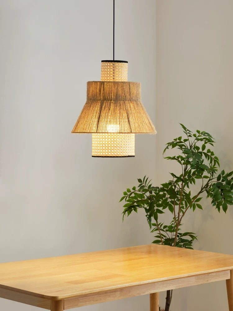 Above an empty wood dining table beside a tall potted plant, this Clérachic pendant glows warm.