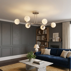 Centered above a navy sofa, this nickel Clérachic chandelier lights a dark-paneled living room.