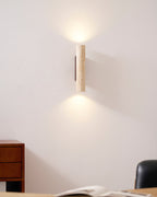 A desk chair and wood dresser sit near this Clérachic wall light, lit, against a plain wall.