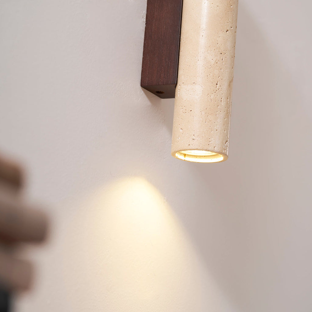 Close view of a hand angling the lower head of this Clérachic wall light, casting light downward.