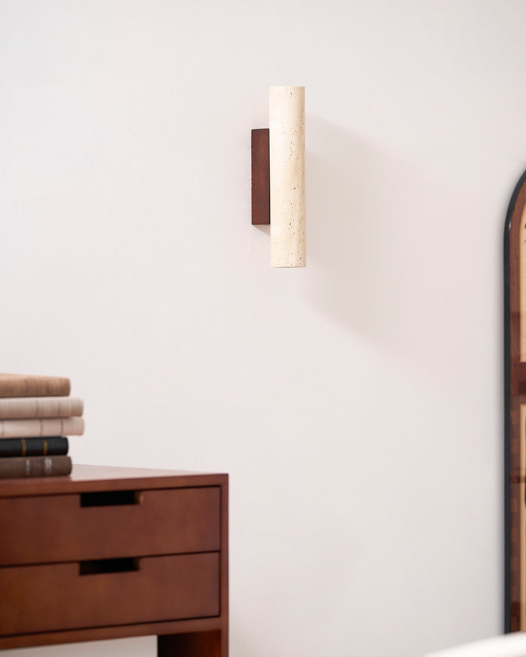 Mounted above a dresser near an arched mirror's edge, this Clérachic wall light stands unlit.