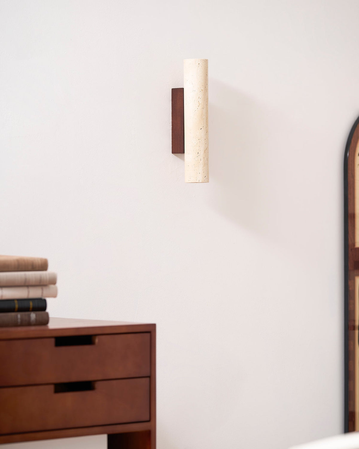 Mounted above a dresser near an arched mirror's edge, this Clérachic wall light stands unlit.