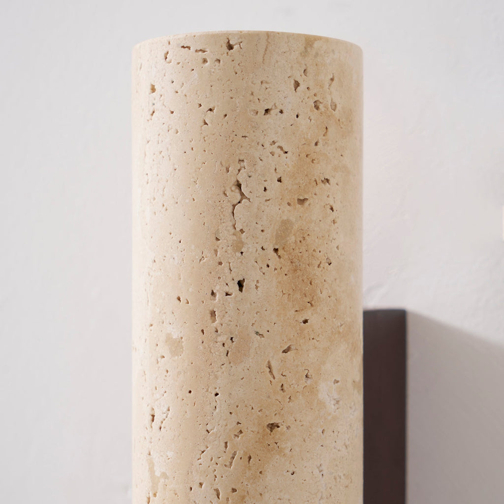 Extreme close view of the travertine stone's pitted texture on this Clérachic wall light.