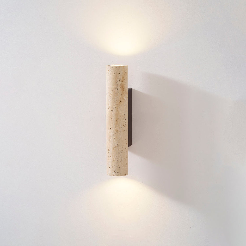 This shorter Clérachic wall light glows lit in the studio, set against a grey backdrop.