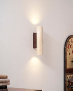 An arched floral-patterned mirror hangs beside this Clérachic wall light, lit, above a wood dresser.