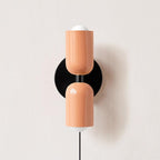 Plug-in wall lamp with coloured shade lighting a styled corner