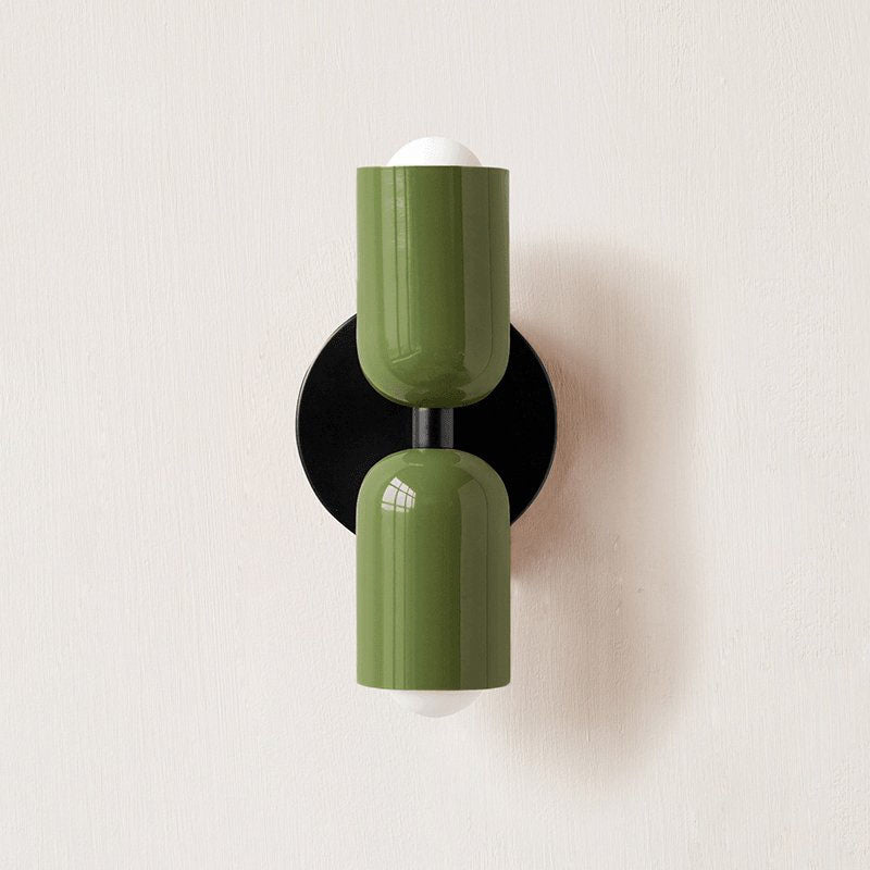 Wall lamp with coloured metal shade glowing in an interior