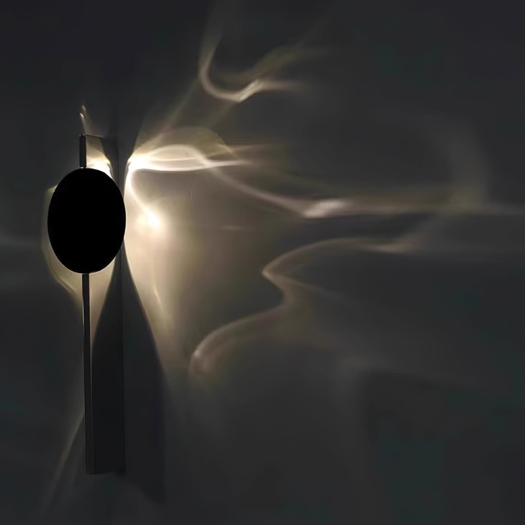 Sculptural chrome wall lamp glowing in a darkened room