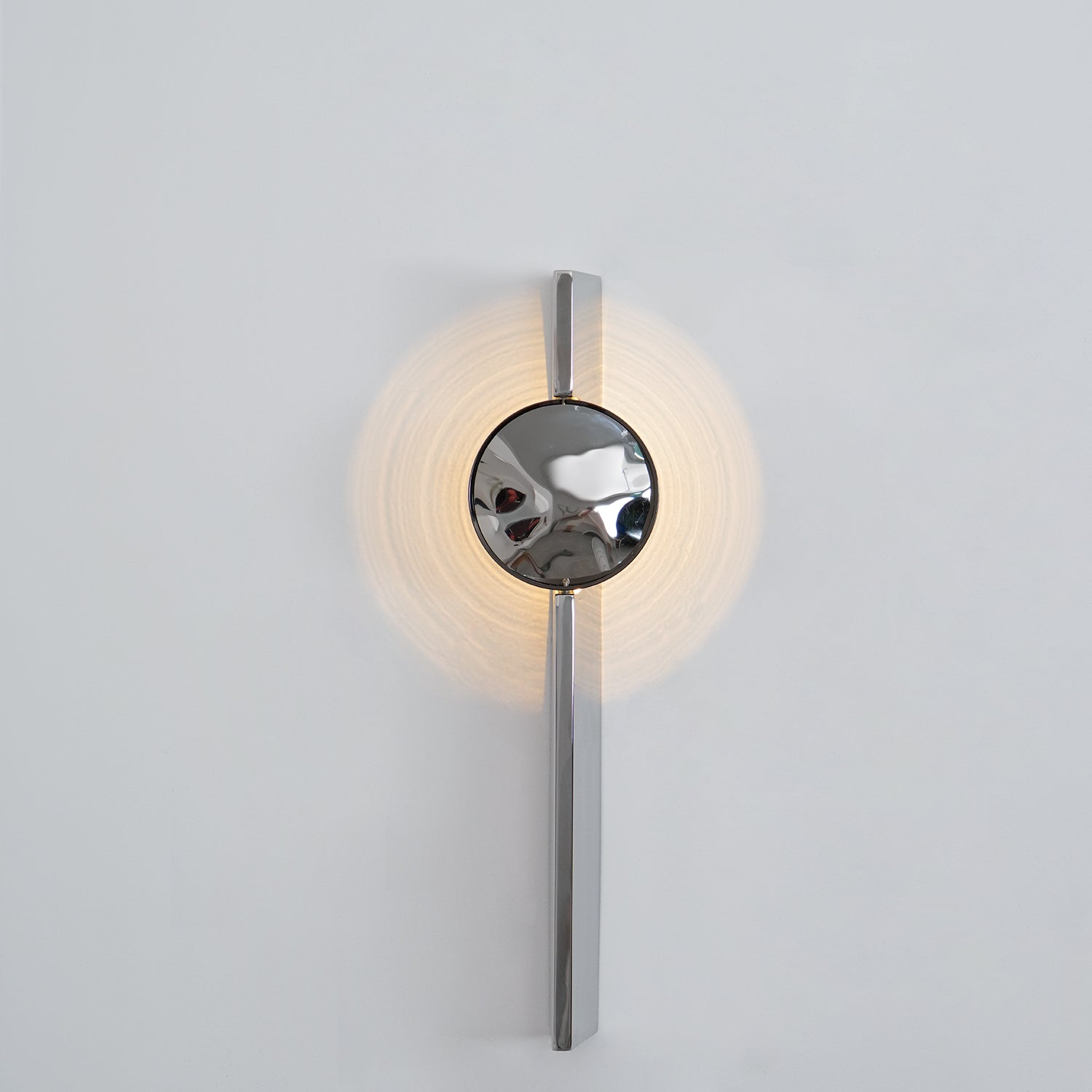 Mirrored chrome wall lamp creating a sculptural light effect