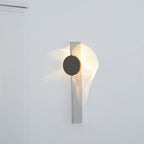 Chrome wall lamp throwing layered light and shadow at night