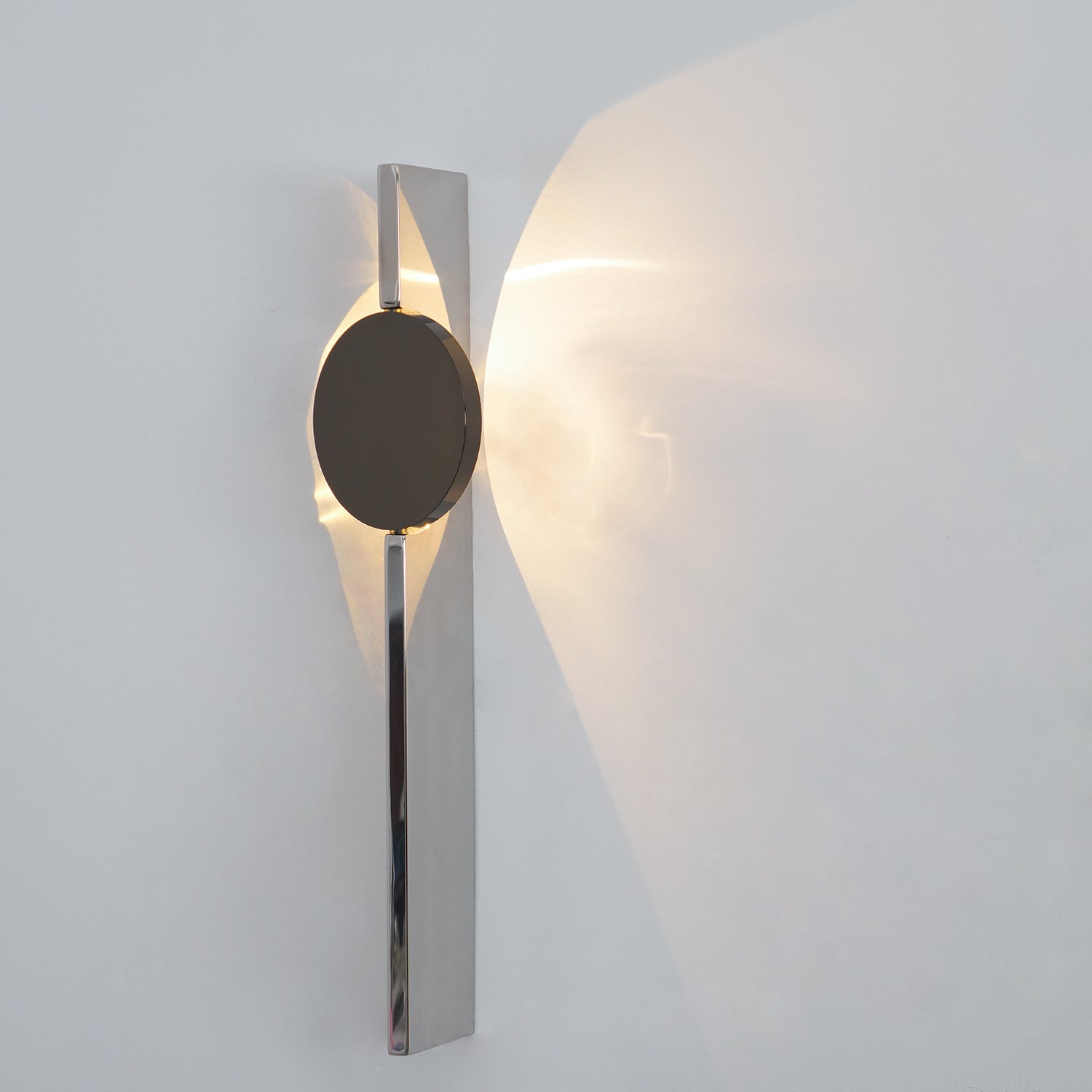 Mirrored wall lamp casting a moving shadow pattern nearby